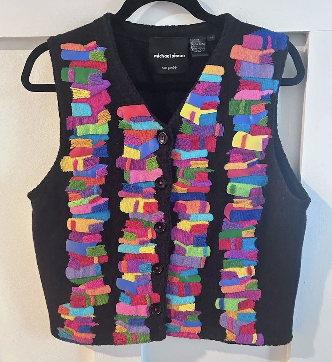 black button-up vest with stacks of colorful books up and down the front