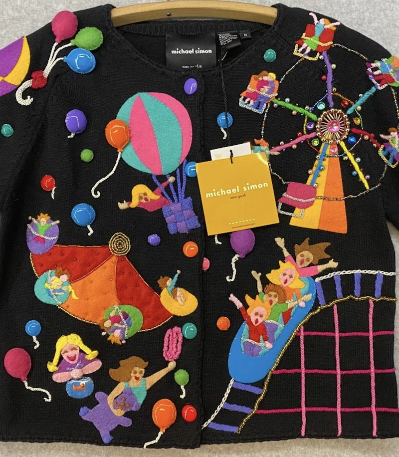 a black short-sleeved cardigan with beading and appliques that show a carnival scene