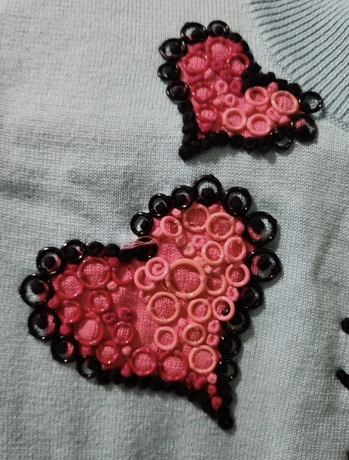 close-up of a knit heart filled in with small plastic circles stitched on
