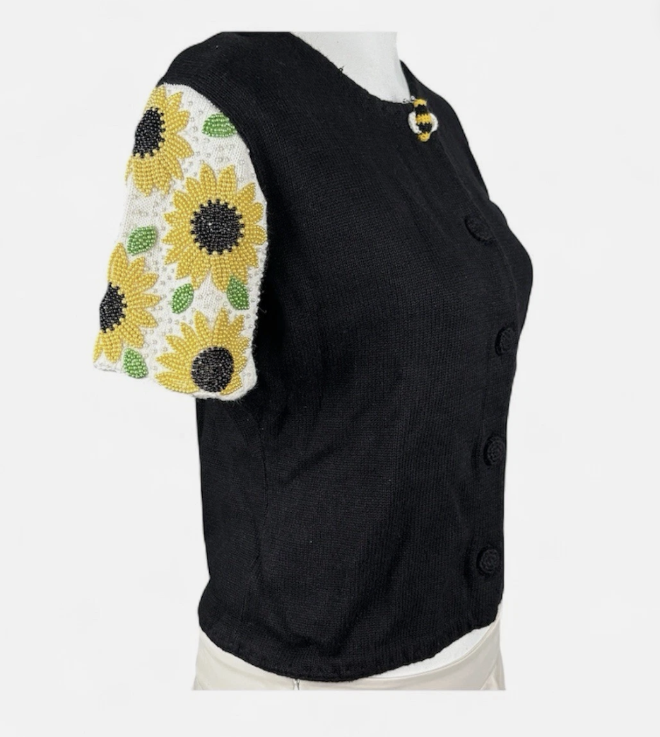 green short-sleeved cardigan with beaded sunflowers on the sleeves and a large bee button at the top